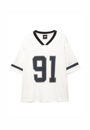 Valkoinen lyhythihainen jalkapallotyyppinen T-paita, jossa on musta V-kaula-aukko, mustia raitoja ja tummanharmaa numero "91" edessä.