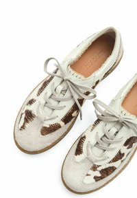 Scarpe stringate realizzate in pelle grigia chiara e suede patrimoniale marrone e bianco con texture. Presentano una morbida soletta beige e una suola in gomma marrone.