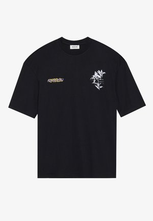 Sort oversized t-shirt med lille hvidt blomstermotiv og gul-lilla forvrænget tekst på foran på brystområdet.