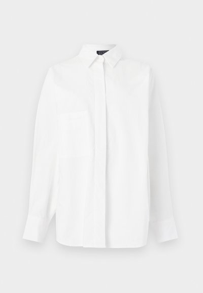 Λευκό πουκάμισο με μακριά μανίκια, γιακά και κρυφά κουμπιά μπροστά, εμφανιζόμενο σε ανοιχτό γκρι φόντο.