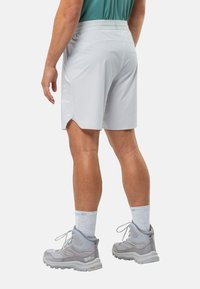 Hellgraue Sportshorts mit seitlichen Belüftungen und glatter Textur, kombiniert mit grauen Wanderschuhen und hellgrauen Socken.