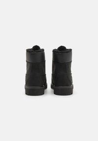 Botines de cuero negro con un suave forro de piel en el cuello, paneles laterales texturizados y una suela de goma robusta.