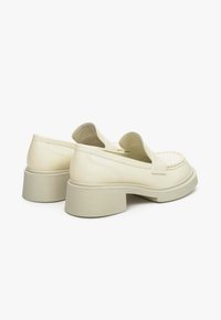Crème leren loafers met een ronde neus, een getextureerde beige zool en een strap over de bovenkant, met stiksel details aan de zijkanten.
