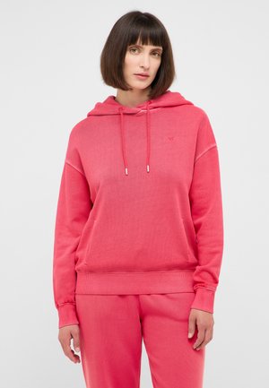 Rosa Kapuzenpullover mit einer Fronttasche, geripptem Saum und Bündchen sowie Kordeln. Kombiniert mit passenden Hosen, die eine weiche Textur aufweisen.
