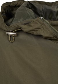 Zeleni ovratnik jakne s djelomično otvorenim patentnim zatvaračem i metalnim zakošem na špagi za podesivo pristajanje.