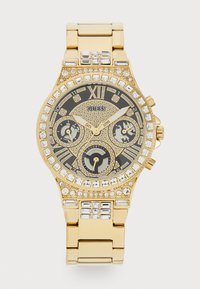 Montre Guess dorée avec un cadran noir, des accents en cristal et des fonctionnalités chronographe. Elle dispose de grands marqueurs d'heure et d'un bracelet poli.
