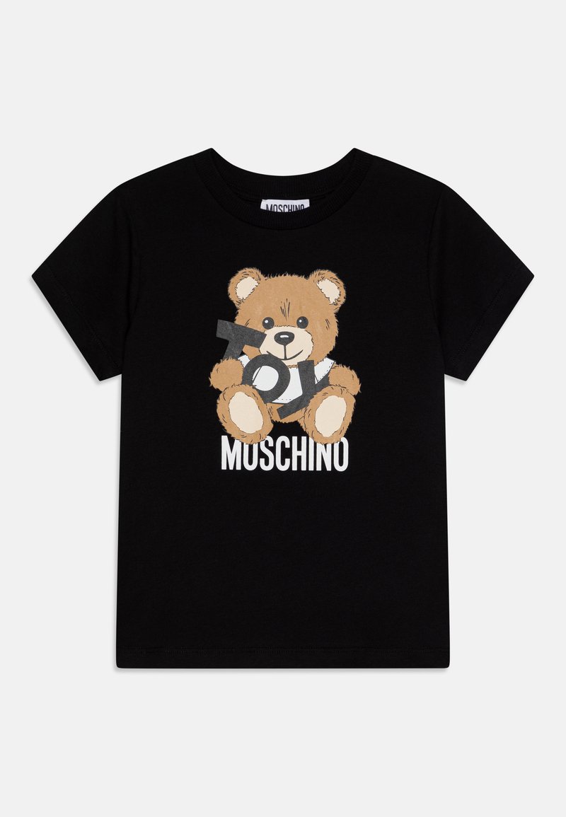 Melna kokvilnas T-kreklā ar teddy bear grafiku un "TOY MUSCHINO" tekstu baltā krāsā. Īsas piedurknes, apaļa kakla izgriezums.