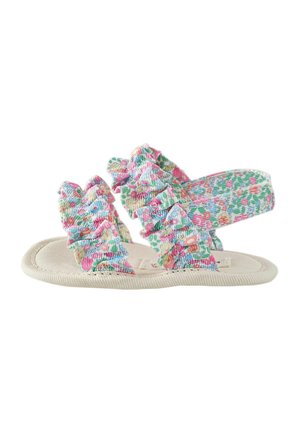 Child's flat sandal with cream sole and multicolored floral fabric straps featuring gathered ruffle details.