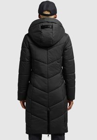 Abrigo de plumas negro con capucha, con diseño acolchado en forma de flecha y una ventilación con cremallera en la parte posterior. Textura suave y lisa con un perfil elegante.