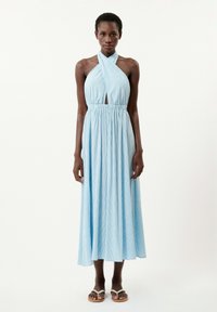 Blau gestreiftes Halsbandkleid mit einem Schlüsselloch-Ausschnitt, elastischem Taillenbund und fließendem Rock. Kombiniert mit einfachen weißen Sandalen.