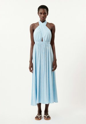 Blau gestreiftes Halsbandkleid mit einem Schlüsselloch-Ausschnitt, elastischem Taillenbund und fließendem Rock. Kombiniert mit einfachen weißen Sandalen.