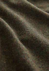Textured wool fabric in dark green, brown, and subtle multicolor fibers, showing a soft, warm appearance with a slightly coarse texture.