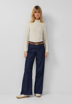 Lichtbeige coltrui, donkerblauwe wijde jeans met bruine riem en beige sneakers. Basis, minimalistisch ontwerp zonder zichtbare patronen.