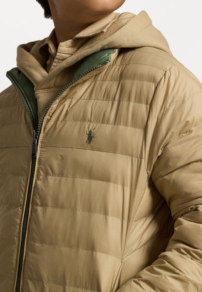Light tan, quilted puffer jacket with a zip front, green accents, and a small logo on the chest. Features a hooded underlayer.