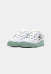 Sneakers albe cu talpă din cauciuc verde, superior din piele, sistem de închidere cu șireturi și accent logo în albastru, roșu și alb pe lateral.