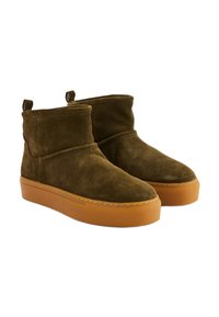 Bottes cheville en daim vert olive avec une semelle plateforme épaisse couleur tan, présentant un détail cousu et des languettes à l'arrière pour un enfilage facile.