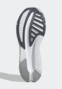 Semelle d'une chaussure de course avec des motifs de bande de roulement noirs, blancs et gris conçus pour l’adhérence et la durabilité sur des surfaces lisses.