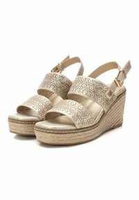 Sandalias de cuña en oro metálico, con patrones florales cortados a láser, punteras abiertas, correas para el tobillo ajustables y una suela de plataforma estilo yute.