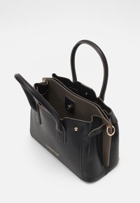 Svart läderhandväska med två handtag, guldfärgad hårdvara och ett beige interiör, med flera fack och en tryckknappslås.