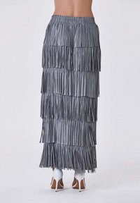 Jupe frangée argentée à plusieurs couches, dotée d'un tissu texturé et d'une taille élastique. Portée avec des chaussures à talons hauts blanches.