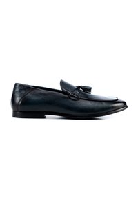 Los mocasines de piel negra presentan un acabado suave, una punta afilada y borlas decorativas en la parte superior. La suela es plana y de diseño sencillo.