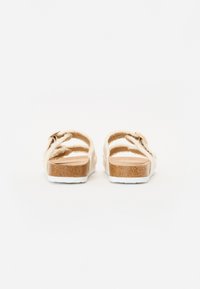Faux fur sandaler med dobbelt justerbare stropper, en naturlig kork såle og en hvit gummisåle. Myk kremfarge med subtil tekstur.