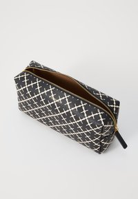 Black and white patterned cosmetic pouch made of textured material, featuring a gold zipper and a brown interior lining.