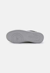 Talpă de pantof neagră din cauciuc cu suprafață texturată gri, având un logo circular și modele complexe în formă de diamante pentru aderență.