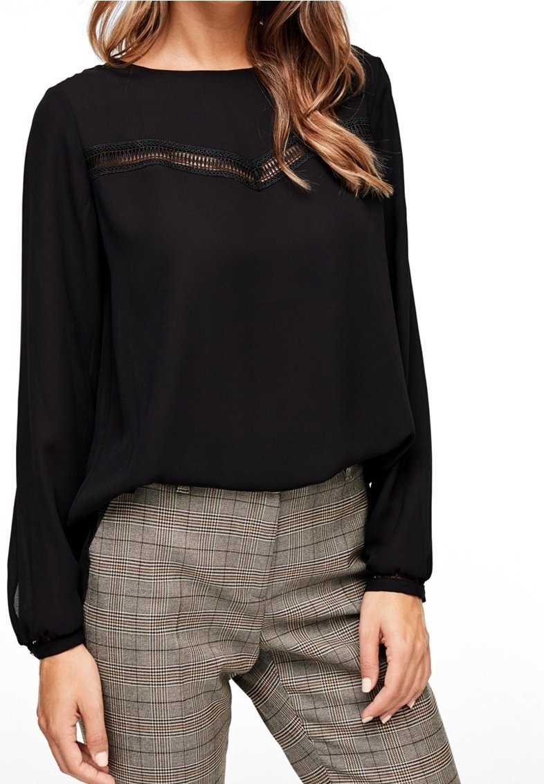 Blusa negra de manga larga con detalles de encaje en el escote, combinada con pantalones de cuadros en tonos beige y marrón. Textura de tela suave.