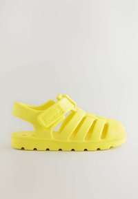 Gelbe Gummisandale mit geschlossenem Zehenbereich, offenem Fersenbereich, verstellbarem Klettverschluss und mehreren Schlitzen zur Belüftung.
