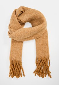 Écharpe en laine beige avec une texture douce, présentant des bords frangés et une forme large et allongée, conçue pour la chaleur et le confort.