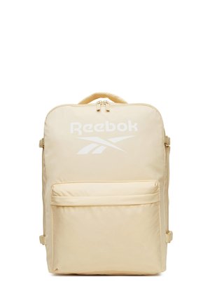 Beżowy plecak Reebok z górnym uchwytem, przednią kieszenią na suwak oraz białym logo na przednim panelu na białym tle.