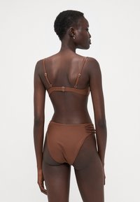 Brun bikinisett med justerbare stropper, baklås og høyhåret bunn med rynkede detaljer på sidene. Glatt tekstur.