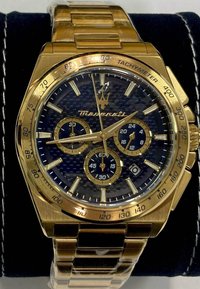 Guldtonad Maserati-klocka med en klocka av blå kolfiber, tre sub-dialer, tachymeter på bezeln och länkad guldkedja.