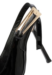 Scarpa con tacco alto in vernice nera, con punta affusolata, dotata di un accento in metallo dorato sulla cinghia alla caviglia e di un tacco elegante e sottile.