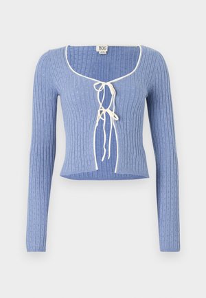 Lys blå ribbet crop topp med lange ermer, med firkantet halsutskjæring og hvite bånd foran. Strukturert mønster over hele.