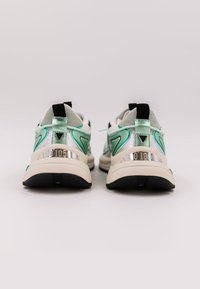 Scarpe da ginnastica sportive con un design argento e verde menta, caratterizzate da una superficie texture, colletto imbottito e un accento riflettente argento sul tallone.