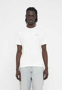 White cotton t-shirt with a crew neck, short sleeves, and a small black logo on the upper left chest. Smooth texture and relaxed fit.