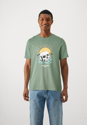 T-shirt en coton vert avec un motif de crâne, un soleil et des vagues, à manches courtes et coupe décontractée.