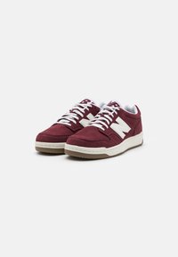 Burgunderfarbene Wildledersneakers mit weißen Akzenten, Schnürdesign und einer strukturierten Gummisohle. Mit einem auffälligen weißen Logo an der Seite.