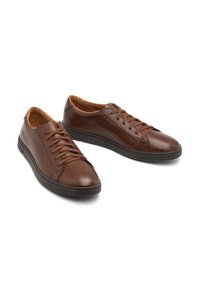 Brązowe skórzane trampki z zaokrąglonym noskiem, tonowanymi sznurówkami i gumowymi podeszwami. Charakteryzują się gładkim wykończeniem i minimalistycznym designem.