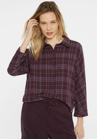 Burgundy plaid shirt in lightweight fabric, features white and light purple lines, button-front closure, and a pointed collar. Long sleeves.