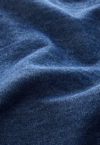 Dunkelblaues Gewebe mit einer glatten Textur, das subtile Variationen in der Farbe und ein feines Gewebe-Muster zeigt, was eine weiche, fallende Erscheinung schafft.