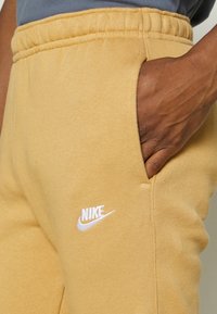 Nike Sportswear CLUB JGGR - Tracksuit bottoms - gold-coloured