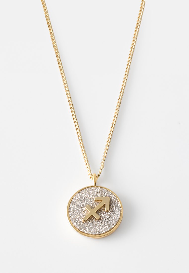 Złoty naszyjnik z łańcuszka z okrągłym zawieszką, która ma teksturowane srebrne tło i wygrawerowany symbol Strzelca w złocie.