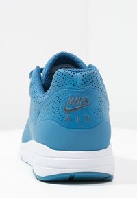 Sneaker Nike Air blu visto da dietro, con tomaia perforata, intersuola bianca e suola blu testurizzata.