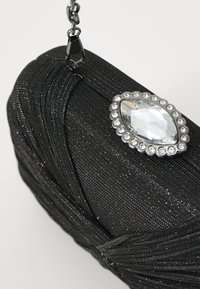 Clutch da sera nera con una finitura metallica texturizzata, caratterizzata da un grande gioiello ovale con un bordo di cristalli e una tracolla a catena.