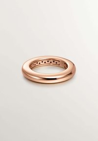 Anillo de metal en oro rosa con un perfil liso y redondeado y un interior que presenta pequeños agujeros espaciados uniformemente. Acabado pulido.