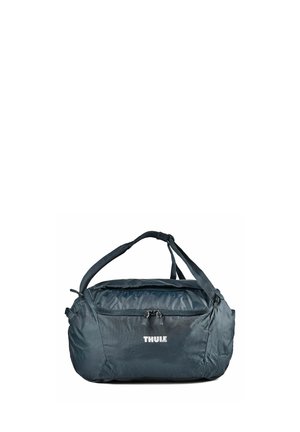 Black Thule duffel bag with top handles and front zippered pocket on white background.