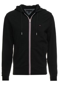 Hoodie noir zippé en mélange de coton, avec une poche kangourou à l'avant, une fermeture éclair rayée blanche et rouge, et une capuche avec cordon de serrage.